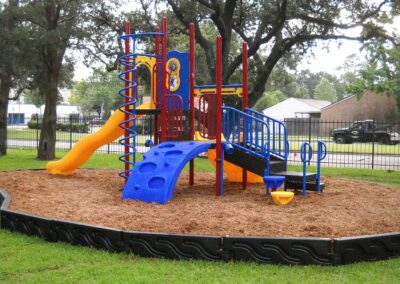 Orange and blue commercial play structure with a slide and climbing wall