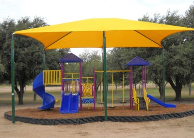 Yellow umbrella shade over a purple and yellow commercial playground