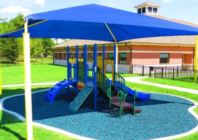 Shaded commercial playground with poured rubber safety surfacing at a school