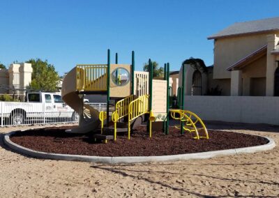 Yellow commercial play structure over red rubber mulch surfacing