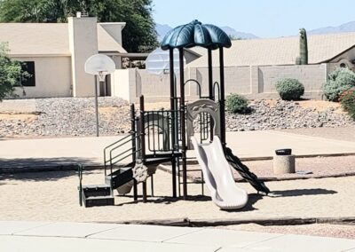 Shaded commercial play structure with a slide in a desert landscaped yard