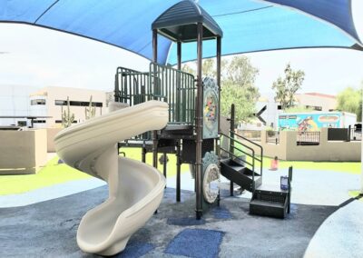 Commercial play structure with a spiral slide over green safety turf
