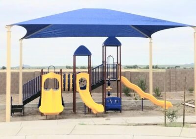 Blue shade sail covering a yellow commercial playground structure
