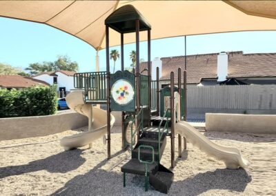 Tan commercial play structure with a spiral slide in a desert courtyard